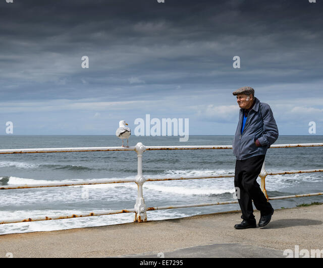 an-older-male-walking-along-whitby-pier-