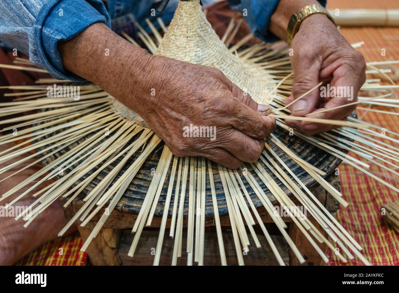 Hands of old artisan craftsman elderly working weaving rattan and ...