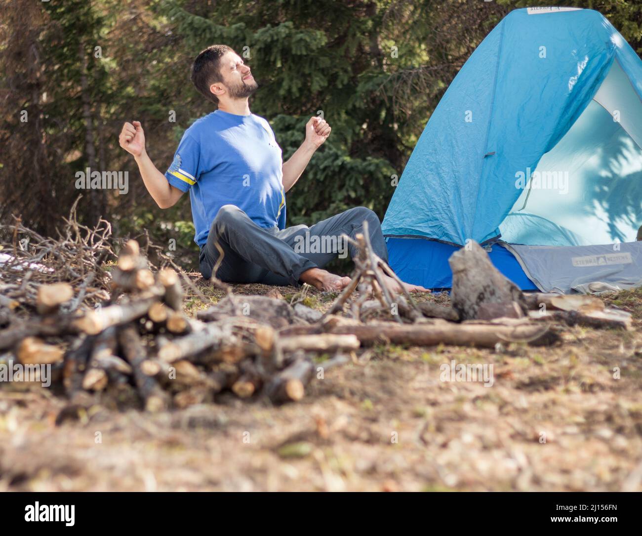 Outdoorsy guy stretching at campsite in the forest Stock Photo - Alamy