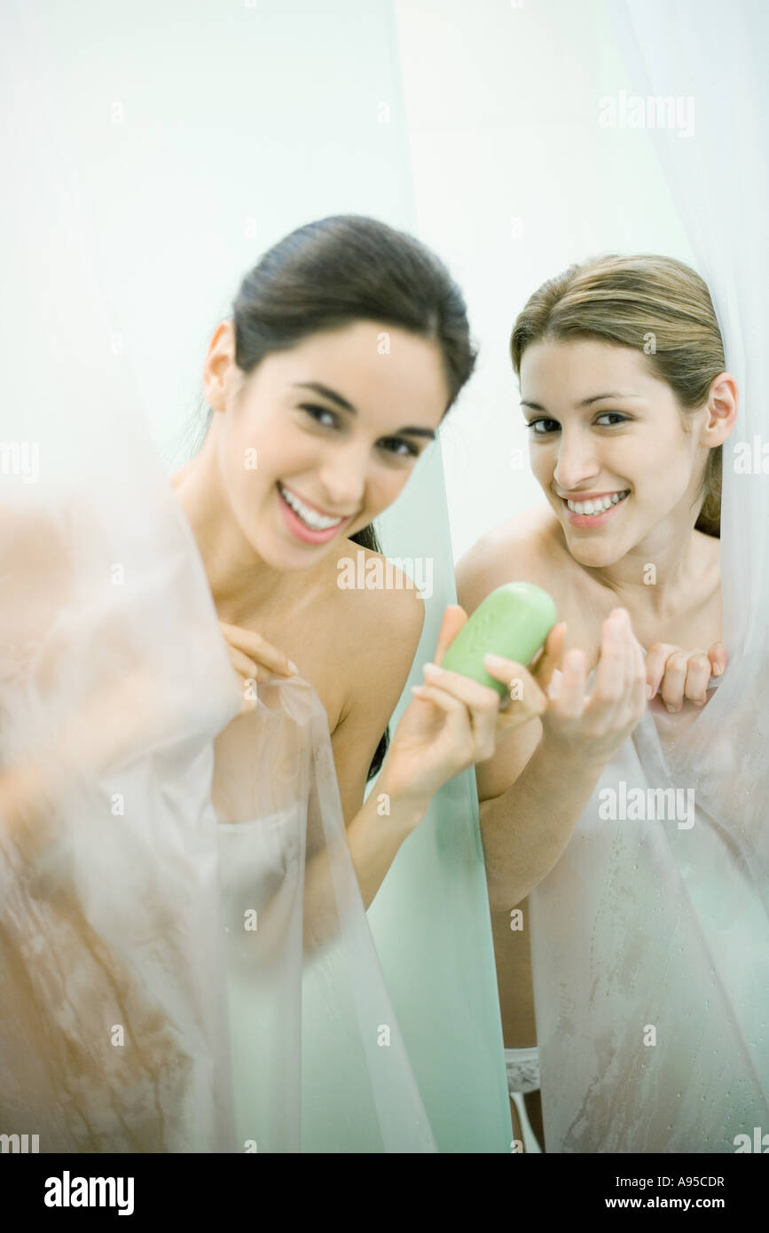 Two Young Women Taking Showers One Handing The Other A Bar Of Soap