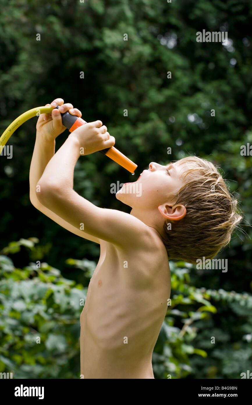 A young boy catching the last drop of water from a garden hose Stock ...