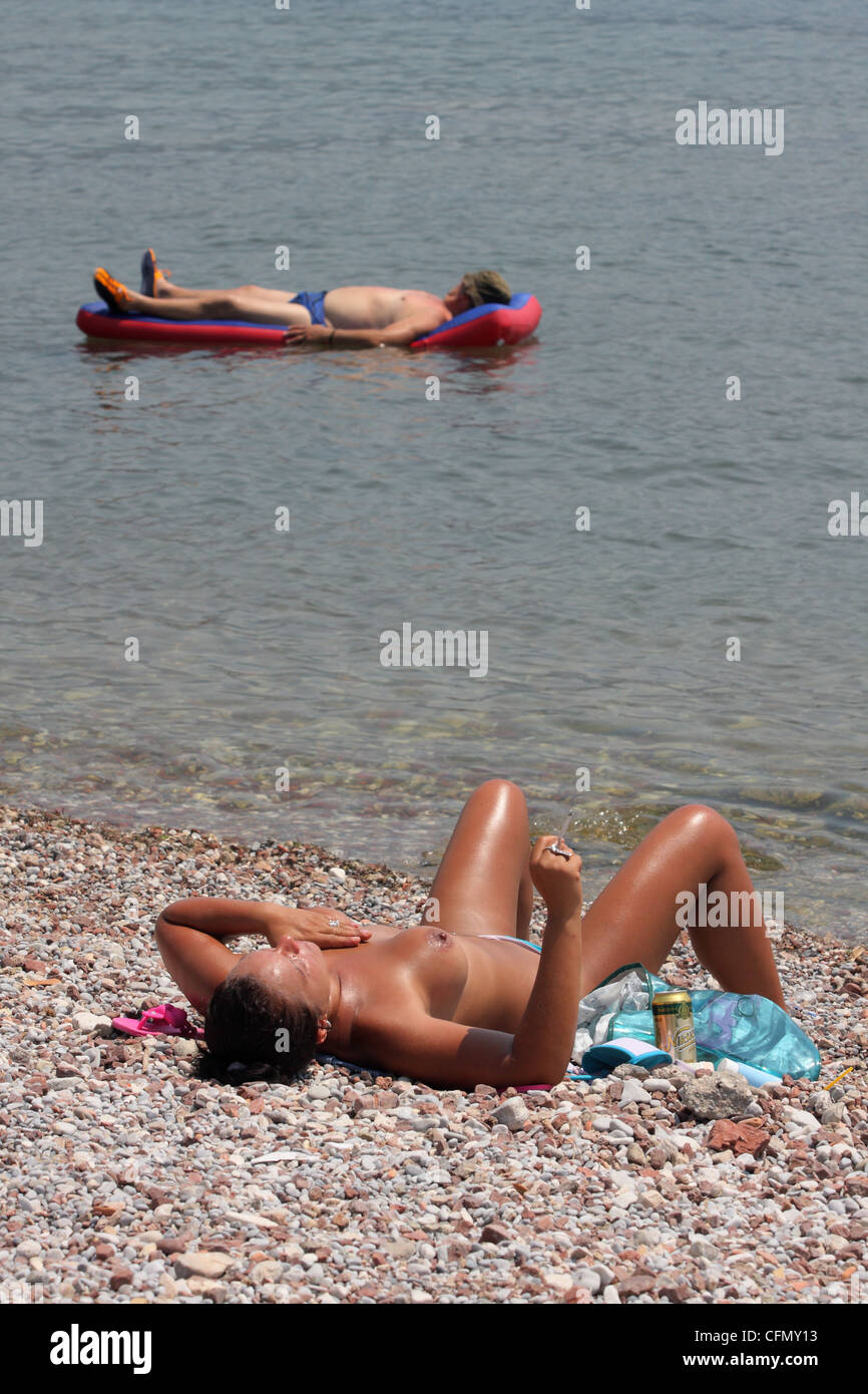 Woman sunbathing on the beach naked, while a man floating on air ...
