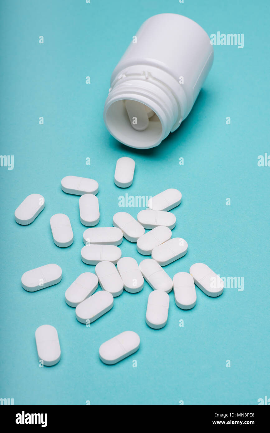 Medication Bottle And White Pills Spilled On Blue Pastel Coloured Background Medication And