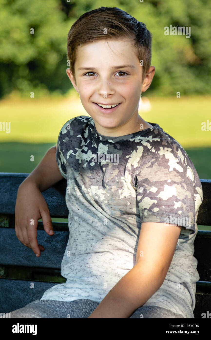 Pre-teen boy sitting outside on a warm summer's day Stock Photo - Alamy