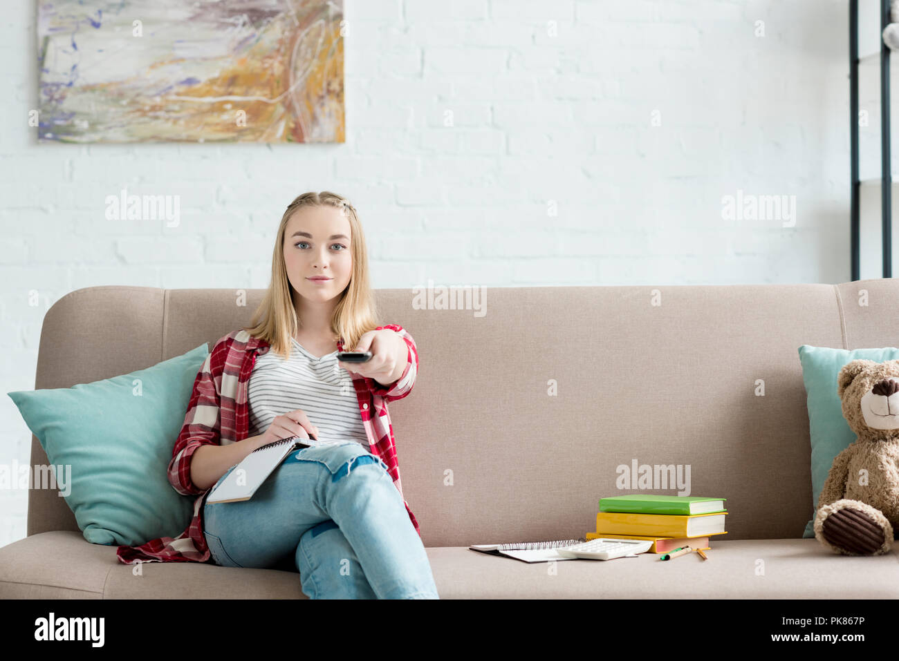 Smiling Teen Student Girl With Remote Control Watching Tv While Sitting