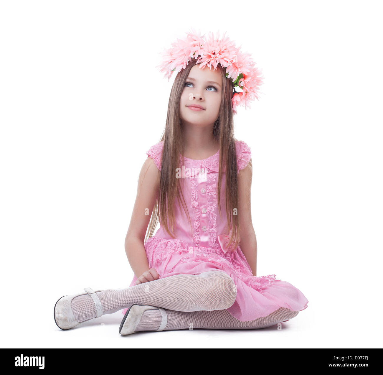 Little girl in pink dress and wreath sitting on floor. Isolated on ...