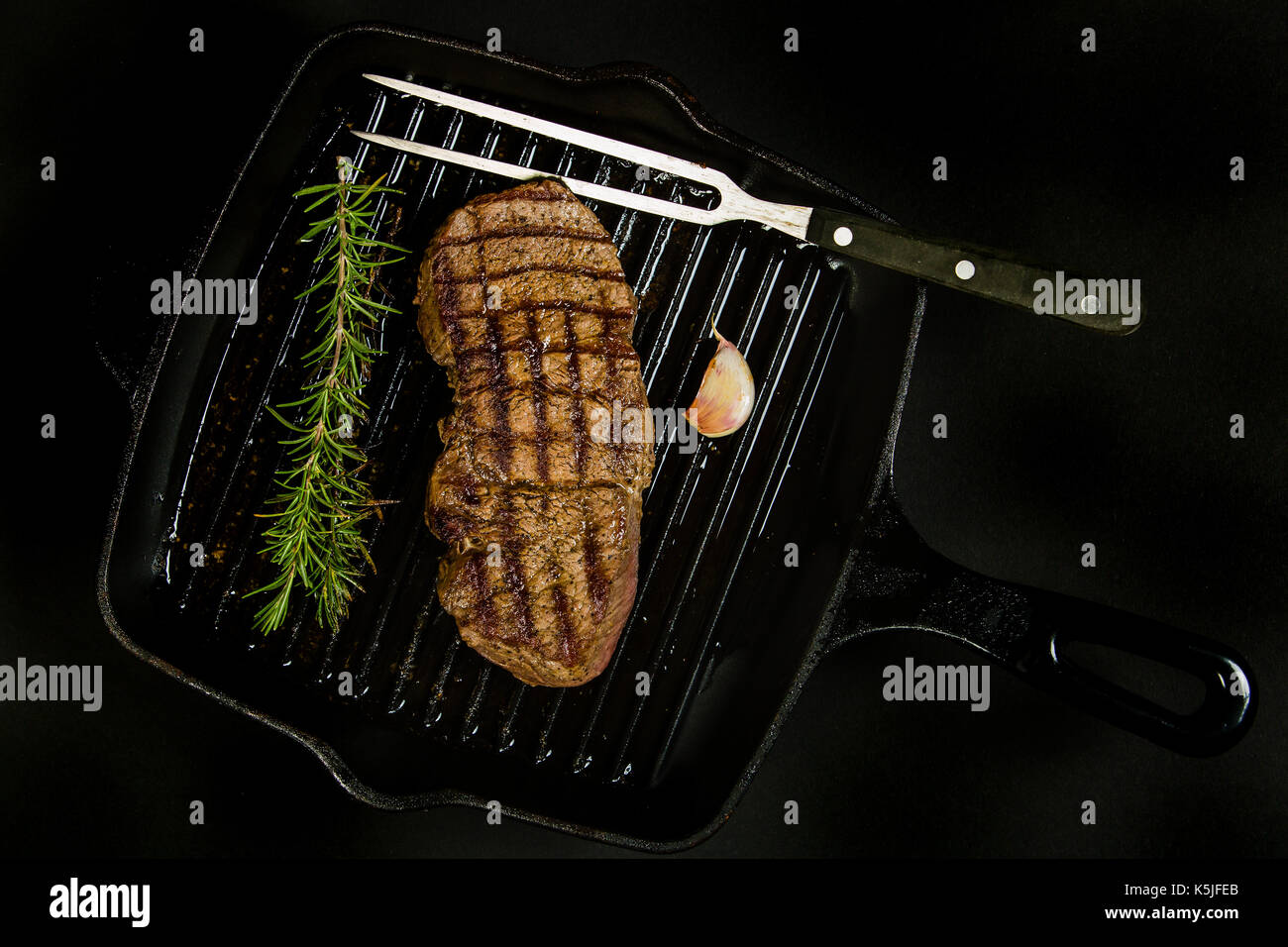 Grilled beef steak in a pan on the black background Stock Photo - Alamy