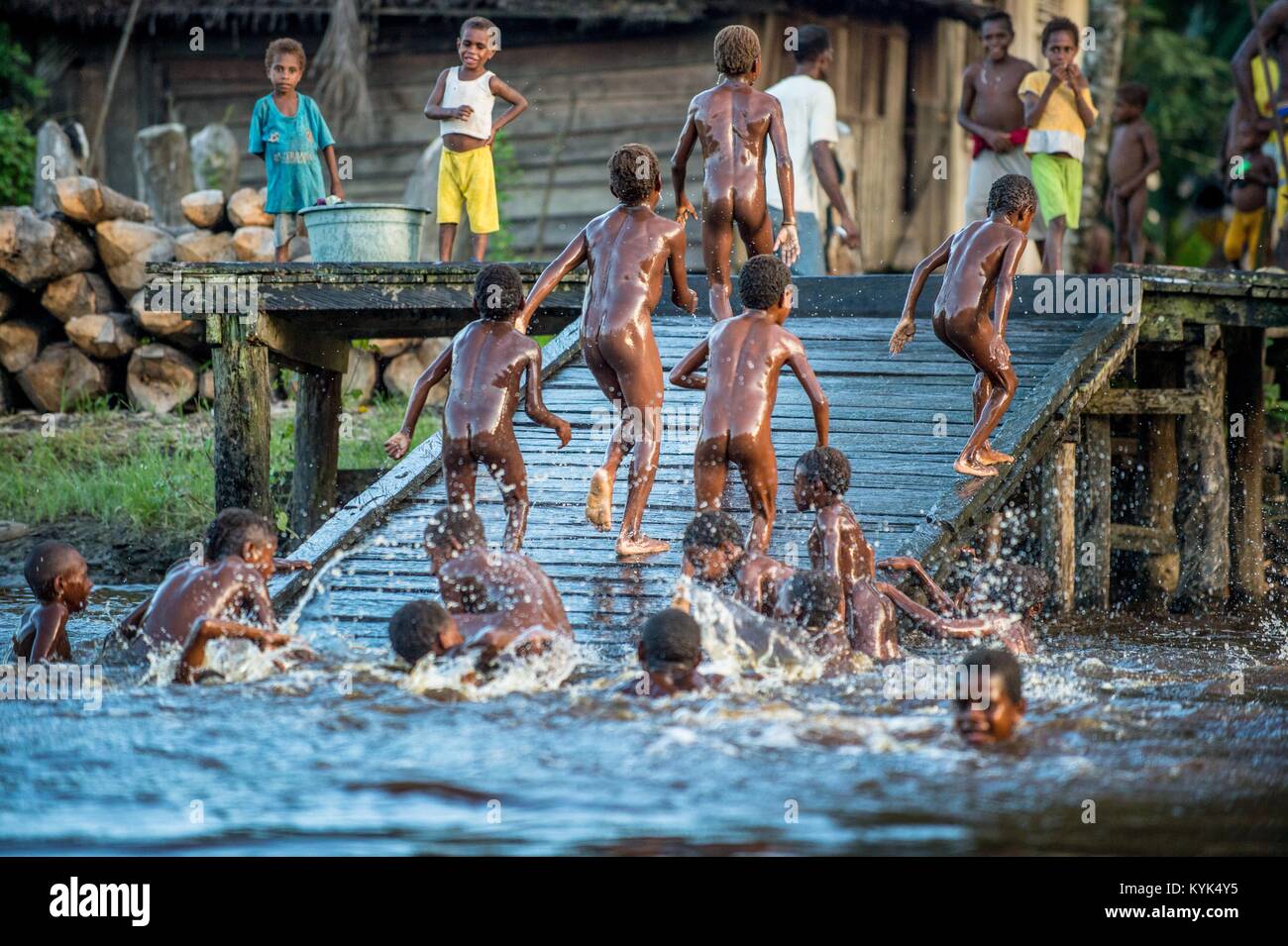 Noisy fun kids. Children of the tribe of Asmat people bathe and swim in