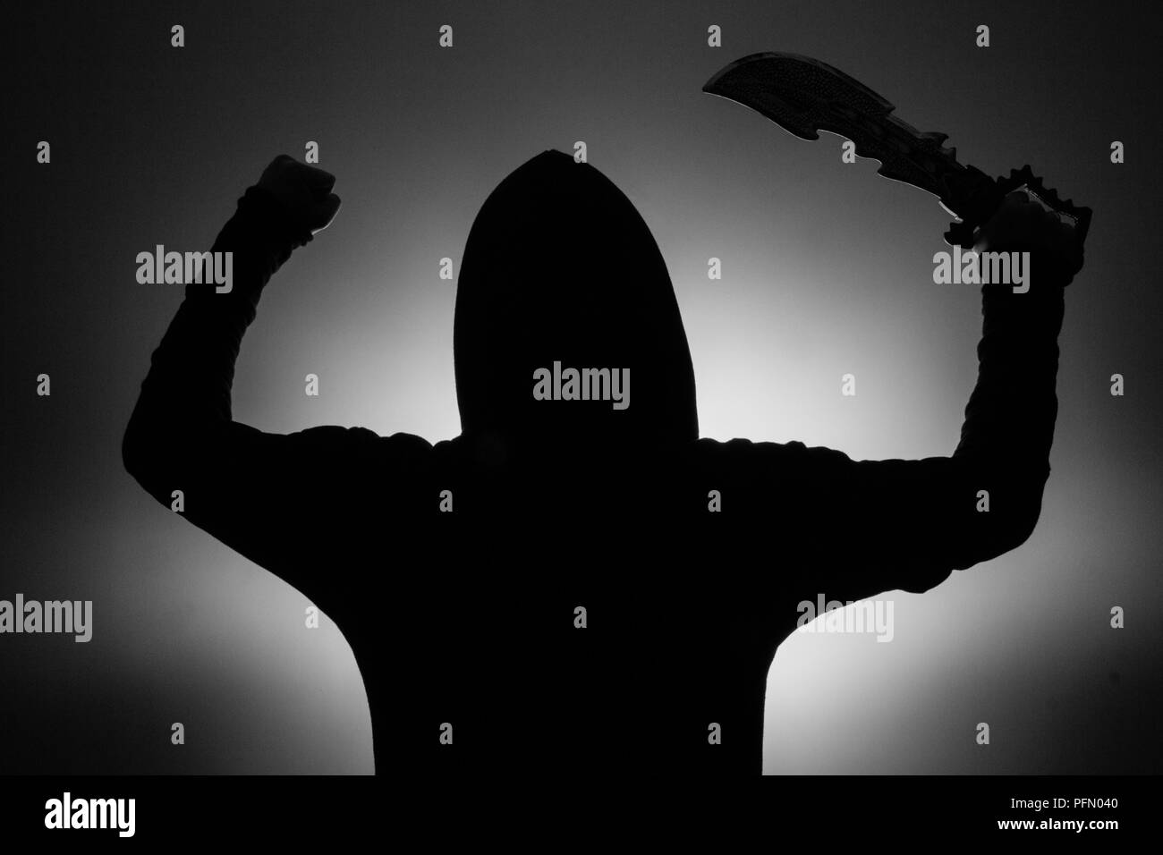 black and white photo: silhouette of a man in a hood holding a fantasy ...