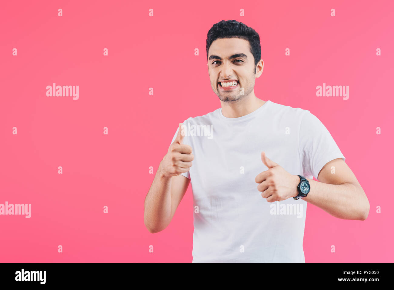 grimacing smiling man showing thumbs up isolated on pink Stock Photo ...