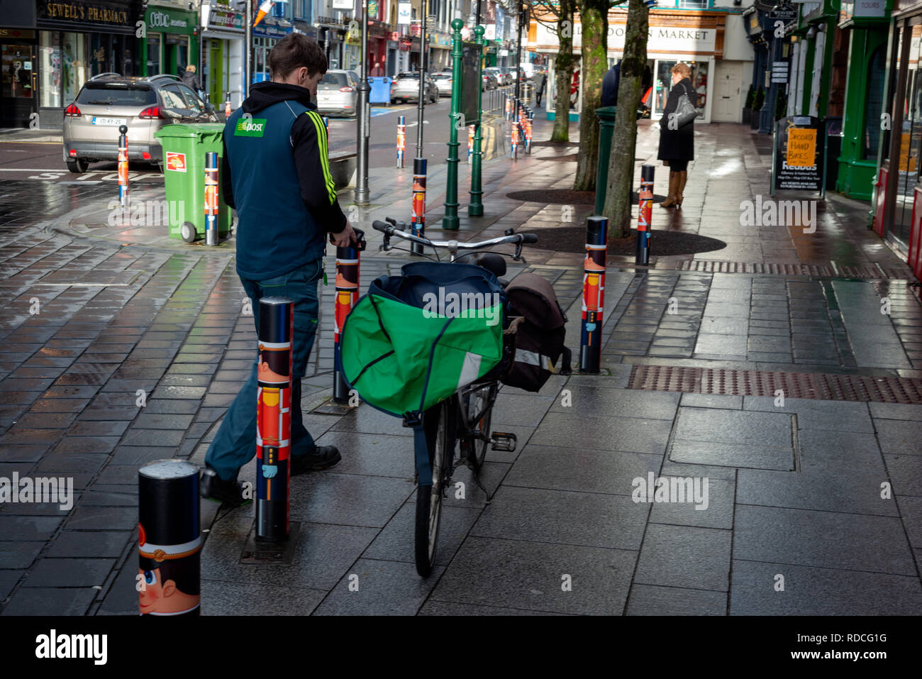 Young postman with push bike on the street, Killarney, County Kerry ...