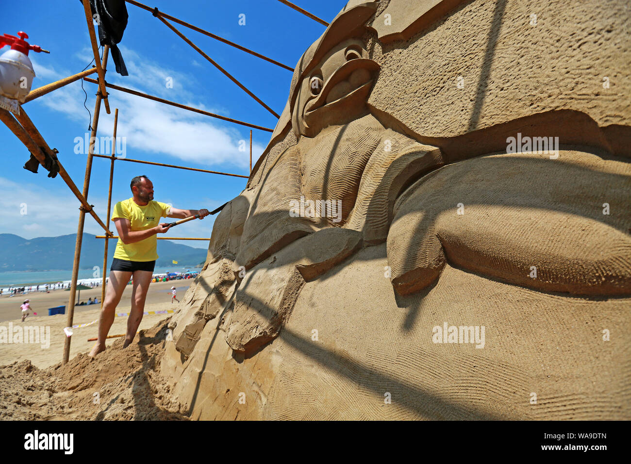Chinese workers carve sand sculptures featuring shape of cartoon ...