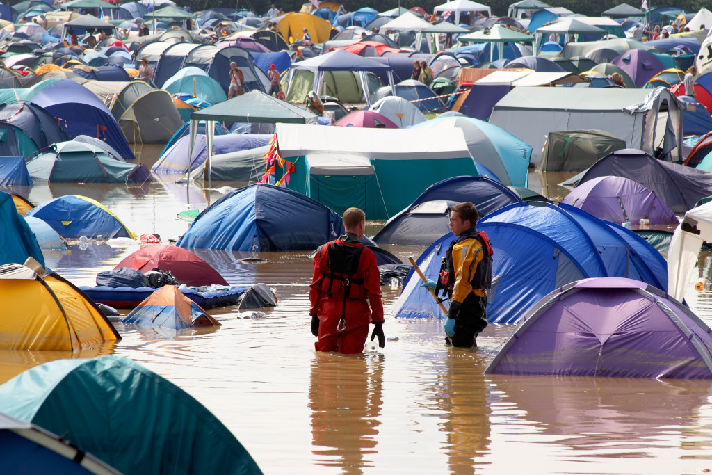 Pennard Hill Camping field with staff in waterproof suits and tents in flooding water and mud following heavy rain at Glastonbury Festival of Contemporary Performing Arts Somerset England UK 2005
